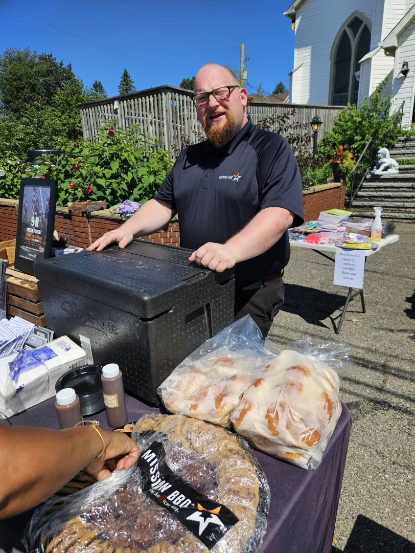 A Mission BBQ team member serving at a table of rolls and cookies outside the Common Ground Ministries center